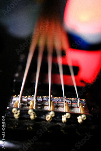 Electric bass guitar 5 strings illuminated with red light, blur background. photo