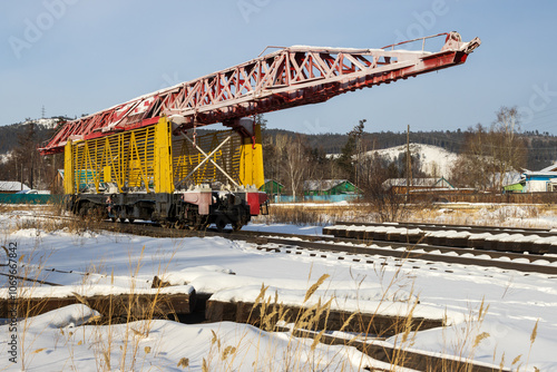 A track-laying monument dedicated to the construction of the Baikal-Amur Mainline (BAM). Severobaikalsk city, Republic of Buryatia, Siberia, Russia. View of a laying crane on rails among the snow. photo