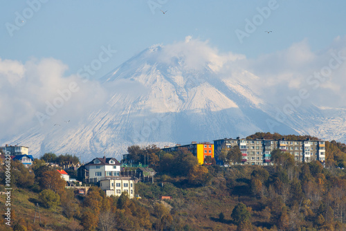 Petropavlovsk-Kamchatsky city, Kamchatka Krai, Russia. View of residential buildings against the backdrop of a volcano. In the distance is the snow-capped Avachinskaya Sopka volcano. Russian Far East. photo