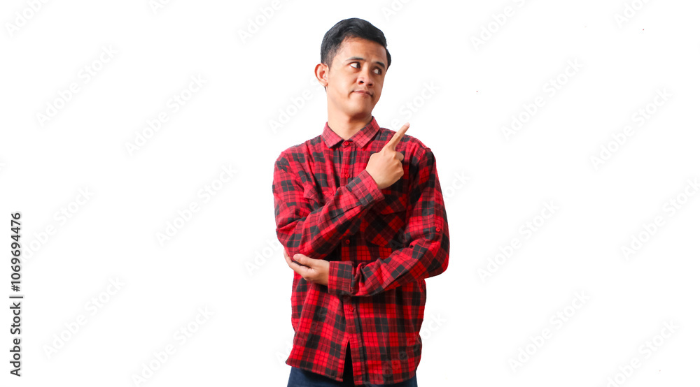 Asian man wearing red checkered casual shirt pointing to the side of empty space with curious expression. Isolated white background. Asian man wearing red checkered casual shirt pointing to the side of empty space with curious expression. Isolated white background.