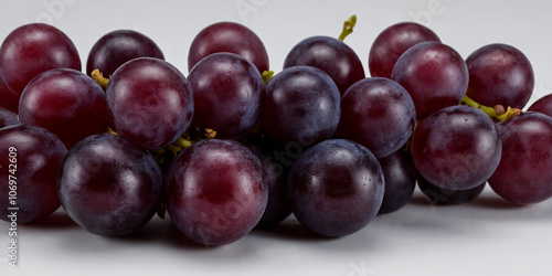 Saftige, glänzende Weintrauben in einem dichten Cluster in dunklem Violett, perfekt für gesunde Snacks oder als Bestandteil in Desserts und anderen kulinarischen Kreationen photo