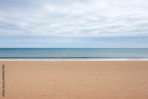 Tranquil beach landscape at dawn with gentle waves lapping the shore and a cloudy sky