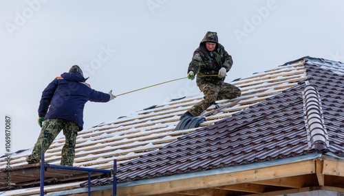 Wallpaper Mural Two men are working on a roof, one of them holding a tape measure Torontodigital.ca