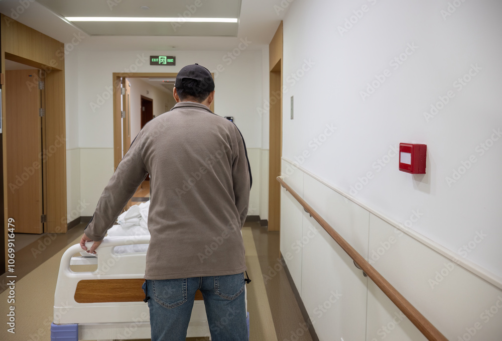 Man pushing a patient lying in bed in a corridor at the hospital.