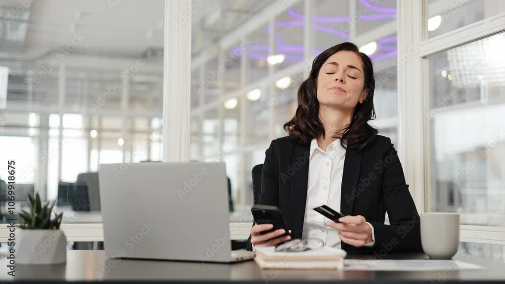 Woman sit at workplace hold credit card use phone try to pay through e-bank app experiences problems due insufficient funds, no money, insecure online payment, scam, fraud, unsuccessful transaction. Woman sit at workplace hold credit card use phone try to pay through e-bank app experiences problems due insufficient funds, no money, insecure online payment, scam, fraud, unsuccessful transaction.
