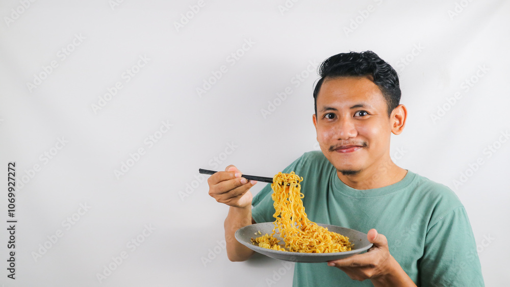 Portrait of Asian man eating delicious fried noodles using chopstick Portrait of Asian man eating delicious fried noodles using chopstick