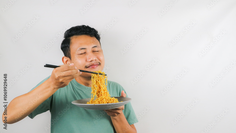 Portrait of Asian man eating delicious fried noodles using chopstick Portrait of Asian man eating delicious fried noodles using chopstick