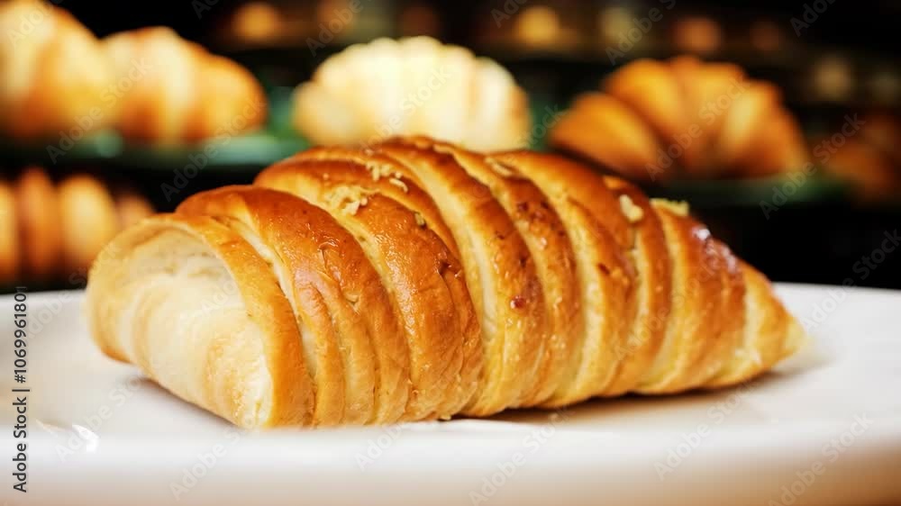 Golden croissant on plate with flaky layers in bakery setting Golden croissant on plate with flaky layers in bakery setting