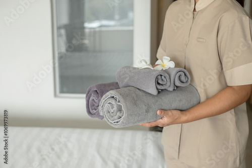 A hotel maid stacked towels on the bed and placed flowers on the towels in a hotel room photo