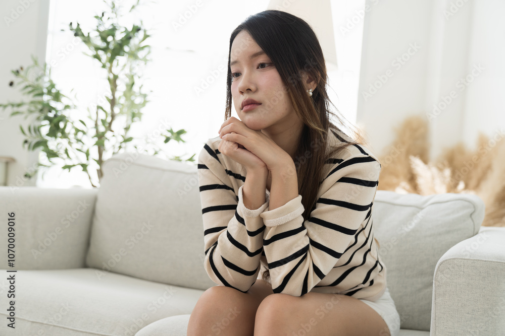 Young Asian woman sitting alone and feel lonely on sofa at home Young Asian woman sitting alone and feel lonely on sofa at home