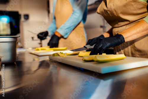 Close up of Middle-aged couple enjoying a cooking class with a chef preparing zucchini for a meal in the kitchen.