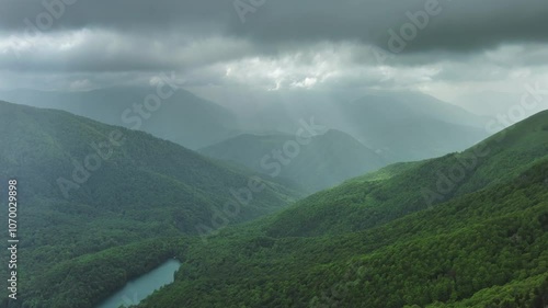 Aerial view of dark clouds and sun rays over summer green mountains landscape, Montenegro, 4k