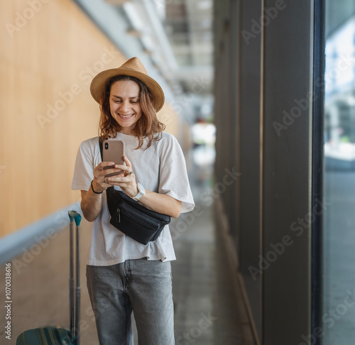Obraz na płótnie Young happy woman traveler in hat with suitcase at airport or train station waiting for travel w salonie