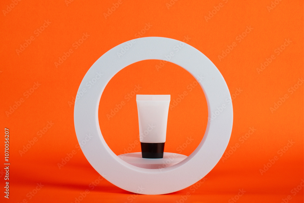 Plastic white tube for cream or lotion. Skin care or sunscreen cosmetic on orange background. Plastic white tube for cream or lotion. Skin care or sunscreen cosmetic on orange background.