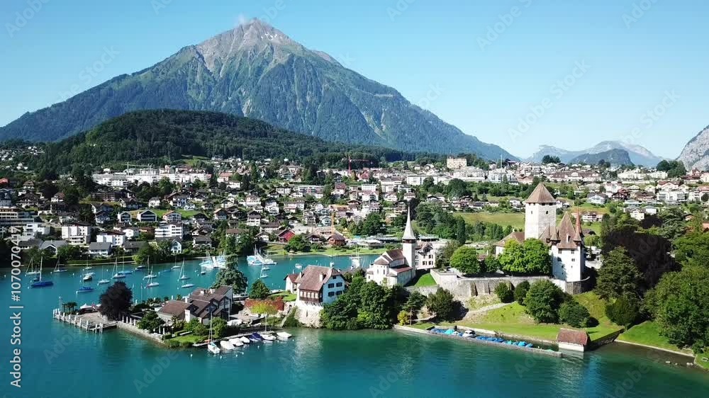 Aerial orbiting revealing the medieval Spiez castle, on the shores of lake Thun - thunersee - , sits beneath the majestic Niesen mountain, Bern, Switzerland Aerial orbiting revealing the medieval Spiez castle, on the shores of lake Thun - thunersee - , sits beneath the majestic Niesen mountain, Bern, Switzerland