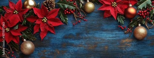 A red poinsettia, gold and silver Christmas ornaments, mistletoe leaves and berries on an old blue denim background with space for text.