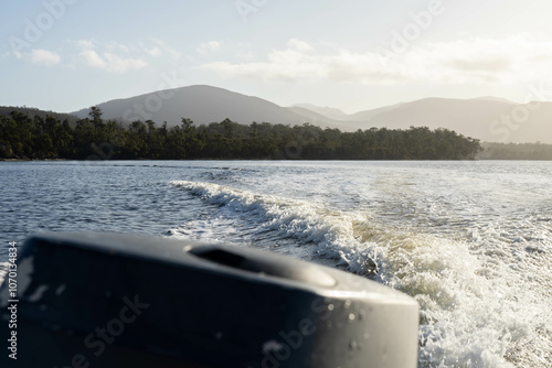 tinny dinghy boat on the water making a wake behind a boat making waves on a river in a national park in australia. beach in summer, dingy going fast photo