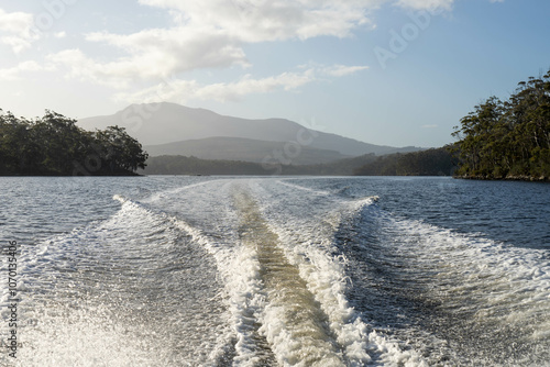 tinny dinghy boat on the water making a wake behind a boat making waves on a river in a national park in australia. beach in summer, dingy going fast photo