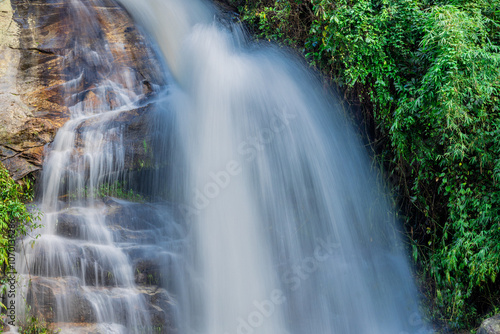 Natural background of waterfall flowing from high place through rocks and rainforest, the water flows in various ways according to the strength and beauty of the natural system.