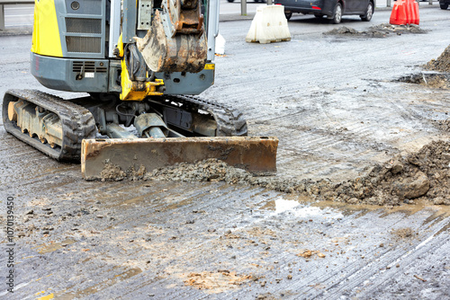 Excavator working on a busy urban road construction site during daylight hours