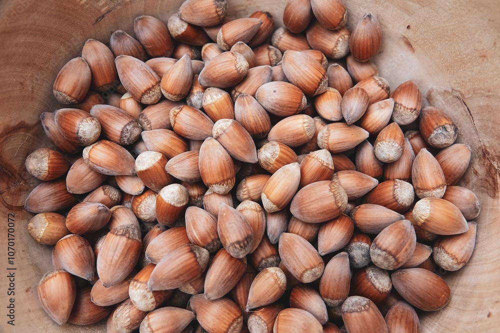 Des noisettes entières dans un récipient en bois, avec effet de lumière crème mate Des noisettes entières dans un récipient en bois, avec effet de lumière crème mate