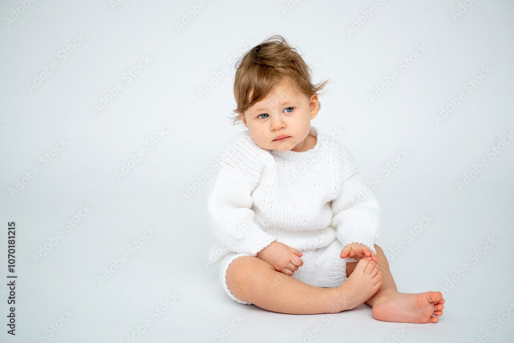 A baby boy on a white isolated background with a place for text is sitting in white knitted clothes. A small happy child in a winter sweater , space for text A baby boy on a white isolated background with a place for text is sitting in white knitted clothes. A small happy child in a winter sweater , space for text