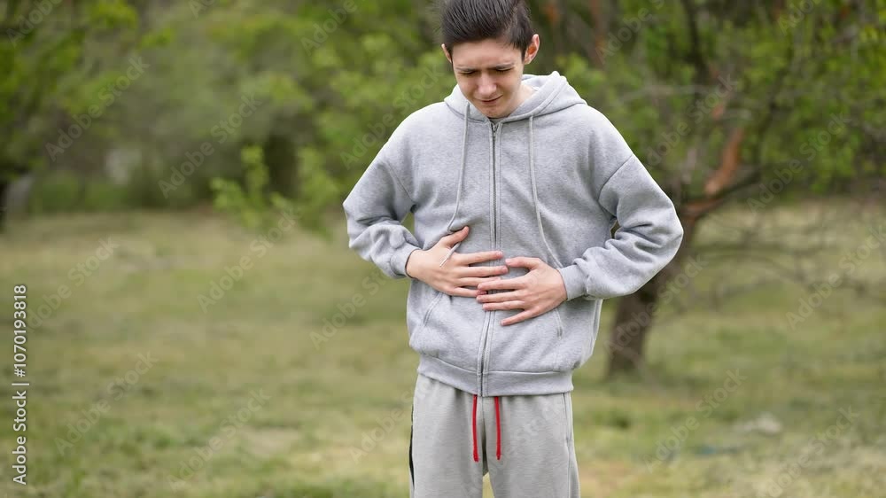 Teenage boy writhing in stomach pain, dealing with intestinal issues infections and diarrhea. Adolescent boy in agony from abdominal pain. Young man contorted in pain from stomach discomfort facing Teenage boy writhing in stomach pain, dealing with intestinal issues infections and diarrhea. Adolescent boy in agony from abdominal pain. Young man contorted in pain from stomach discomfort facing