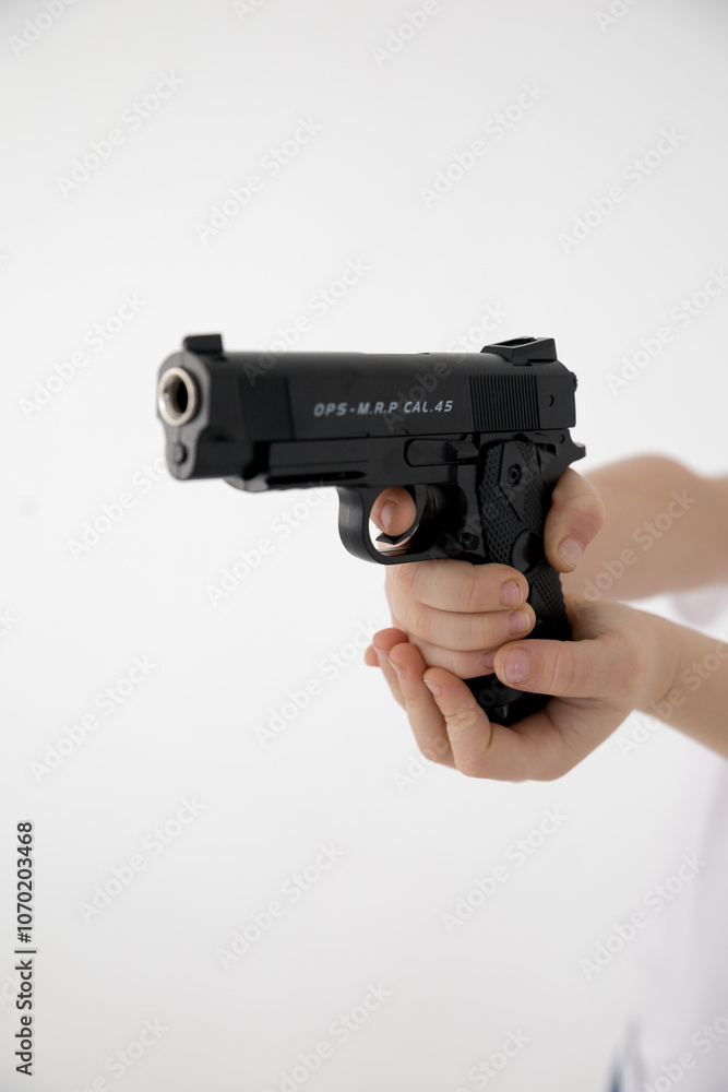 Close up male hand holding black plastic toy gun on white background.toy gun in hand ON A WHITE BACKGROUND Close up male hand holding black plastic toy gun on white background.toy gun in hand ON A WHITE BACKGROUND