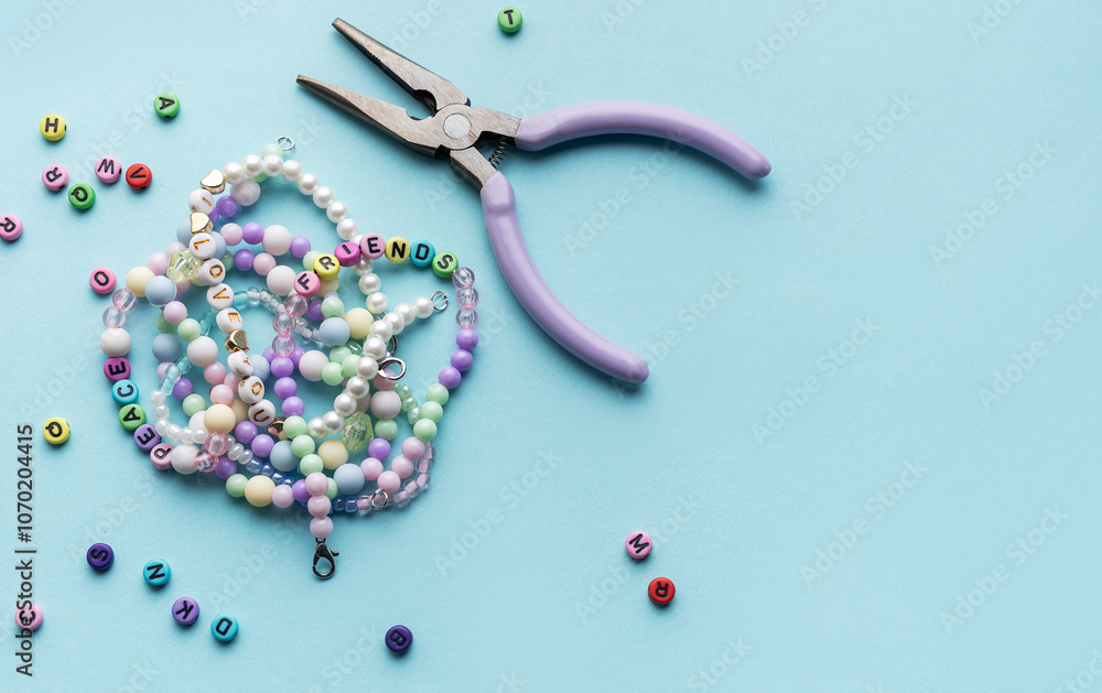 Colorful assortment of beads and jewelry-making tools on a blue surface with completed bracelets