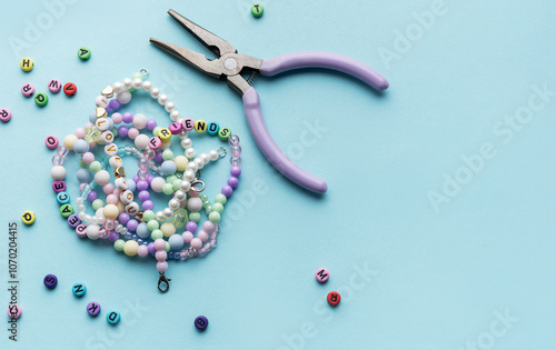 Obraz na płótnie Colorful assortment of beads and jewelry-making tools on a blue surface with completed bracelets w salonie