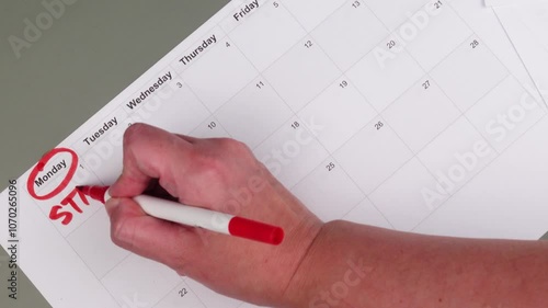 Monthly calendar with red marker circling Monday, writing word Start, concept of planning and beginning fresh, start of week. Setting goals, organizing tasks, visualizing motivated start on Monday.