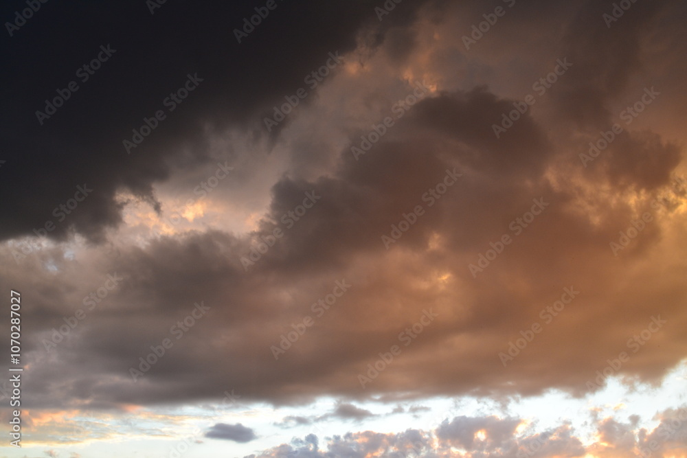 Obraz premium Bright unusual sunset city landscape orange pink rays above cityscape. Brutalist panel buildings appear as black silhouettes against a fiery orange-yellow sky dramatic lighting dark rain storm clouds