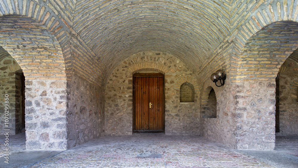 Obraz premium The Upper Caravanserai courtyard in Shaki, Azerbaijan, boasts magnificent stone walls and an arched ceiling, showcasing the area's rich architectural heritage.