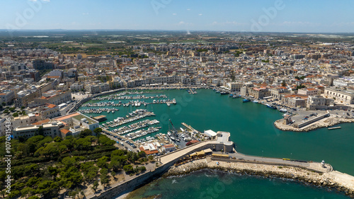 Aerial view of the port of the city of Trani, in Puglia, Italy. It is a small tourist seaport on the Adriatic Sea. There are many boats anchored in the clean water of the harbour.