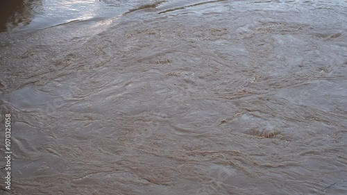 A body of water that is brown and murky. The water appears to be murky due to the presence of mud and debris. The water is also moving, which could indicate that it is a river or a stream