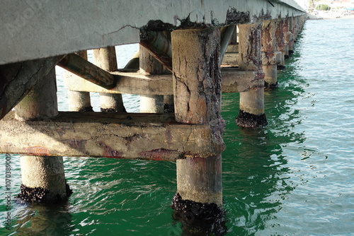 Obraz na plátne Concrete pier showing signs of deterioration and corrosion in green water