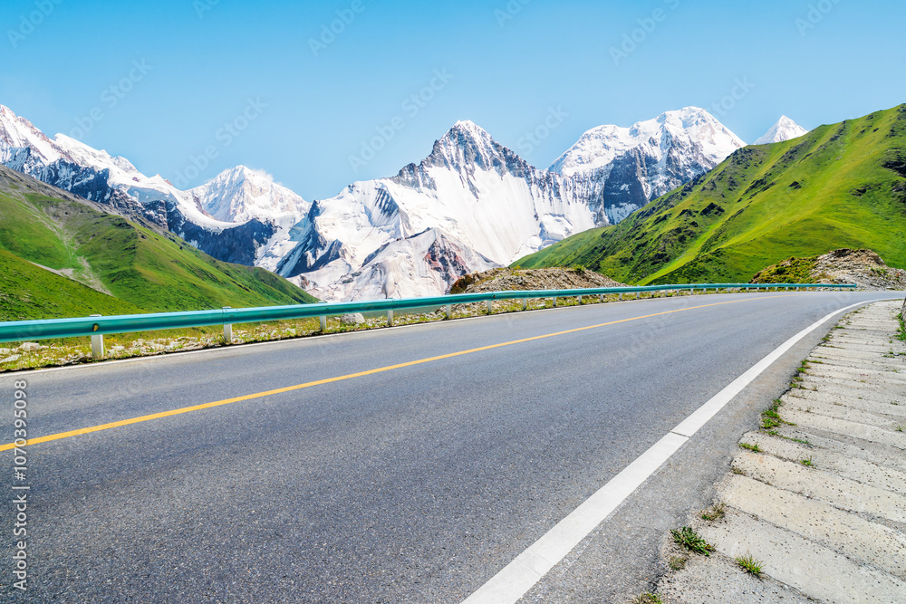 Fototapeta premium Asphalt highway road and green grass with snow mountain natural landscape under blue sky. road trip.