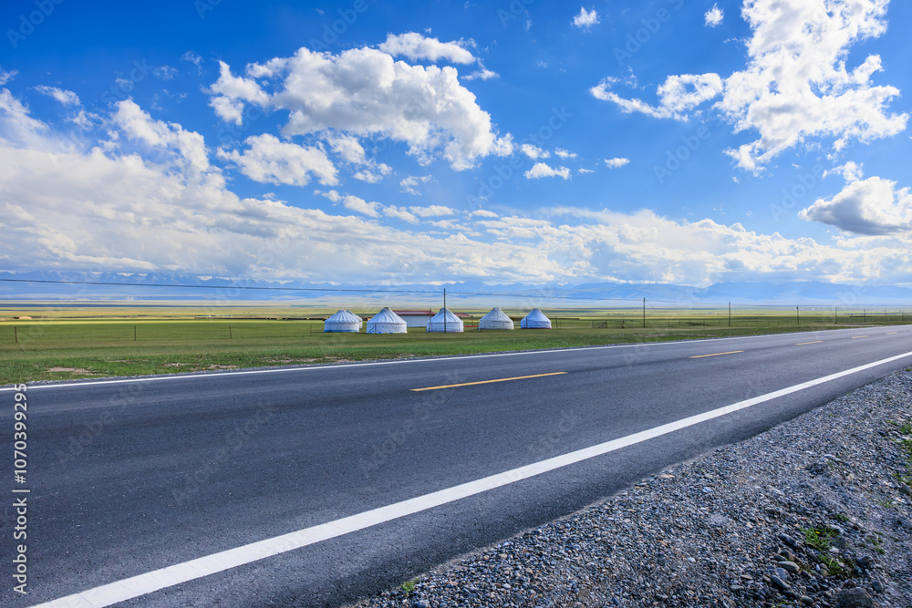 Country Road and green grassland nature landscape under blue sky. Road trip. Country Road and green grassland nature landscape under blue sky. Road trip.