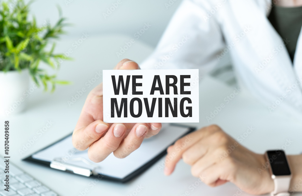 A person holding a card that says We are moving A person holding a card that says We are moving