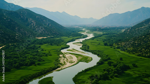 A winding river flows through a verdant valley, surrounded by lush green hills.