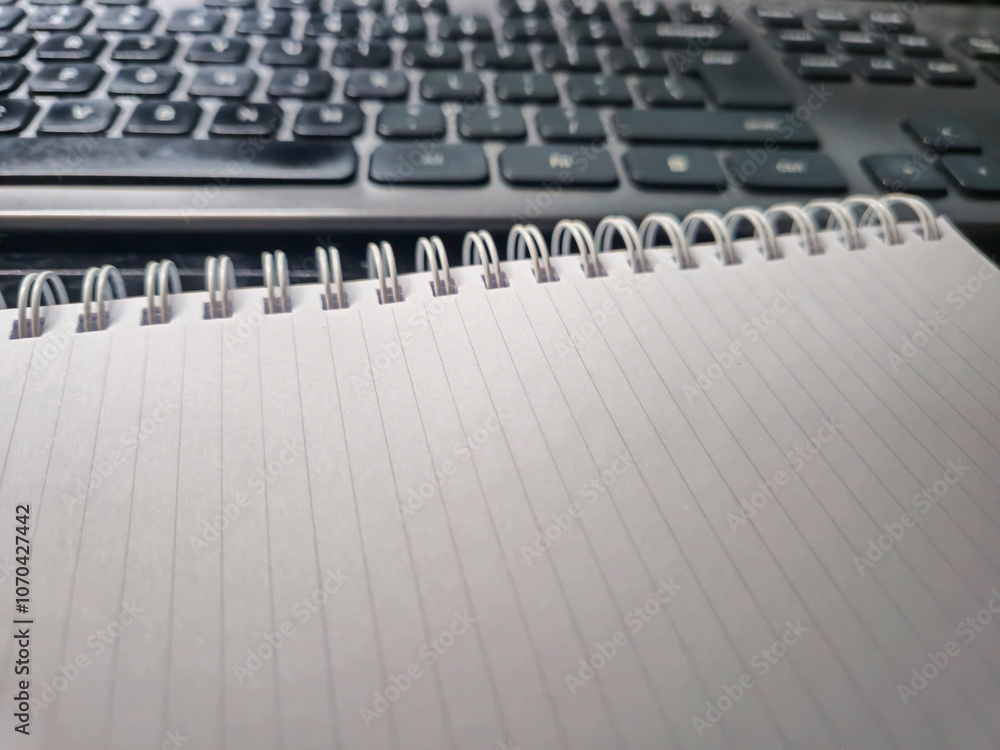 A blank notebook lies beside a black keyboard, perfect for creative ideas and notes. Ideal for writers, students, or office use. A blank notebook lies beside a black keyboard, perfect for creative ideas and notes. Ideal for writers, students, or office use.