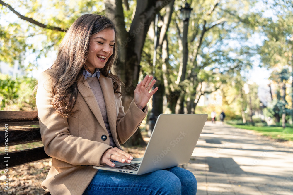 Young businesswoman on video call using laptop outdoors in city park, engaging in remote work. Professional woman online connecting with employees and clients for global business. Young businesswoman on video call using laptop outdoors in city park, engaging in remote work. Professional woman online connecting with employees and clients for global business.