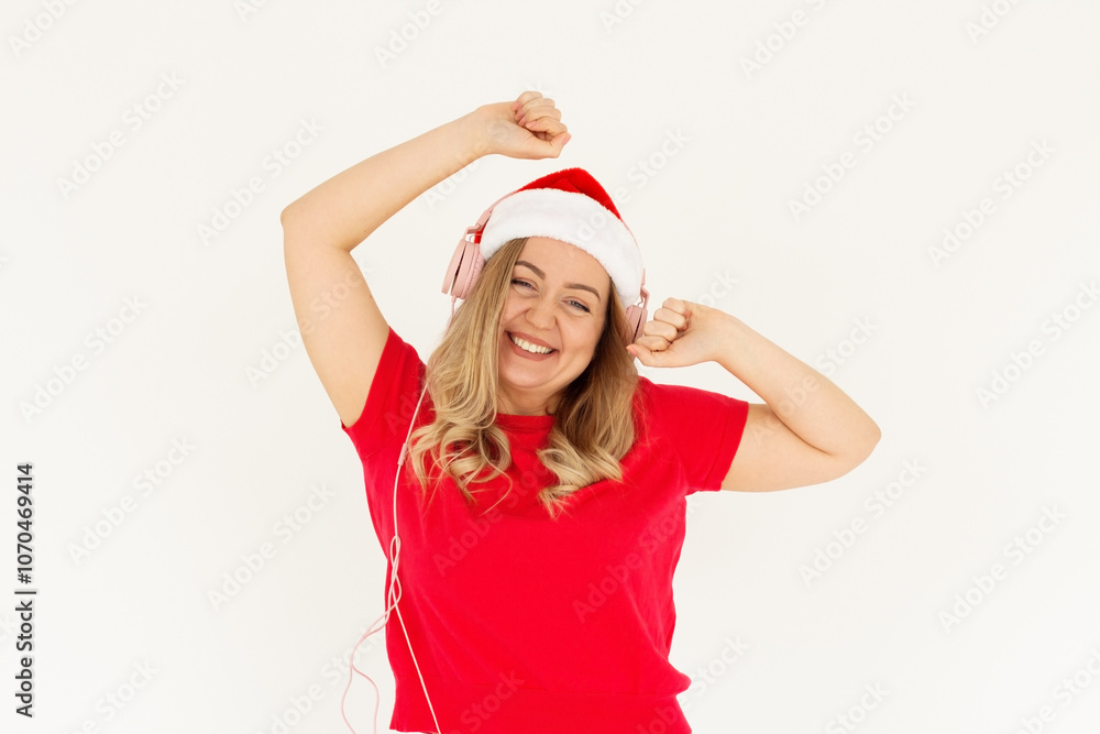 Funny young Santa woman in red t-shirt, hat listening music with headphones dancing rising hands isolated on white background studio portrait. Happy New Year celebration holiday concept Funny young Santa woman in red t-shirt, hat listening music with headphones dancing rising hands isolated on white background studio portrait. Happy New Year celebration holiday concept
