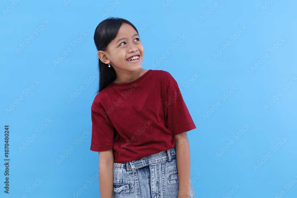 Happy asian little girl standing while looking something at empty space. Isolated on blue Happy asian little girl standing while looking something at empty space. Isolated on blue