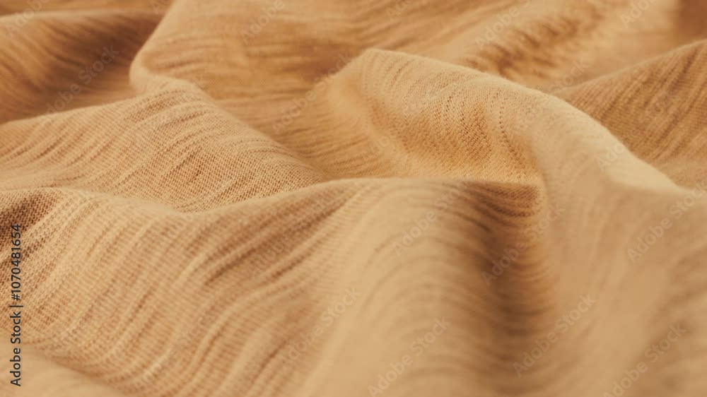 Close-up view of the soft folds of the thin beige cotton jersey cantaloupe shade. The textile background  rotates on the display case. Background on the theme of fashion, design.