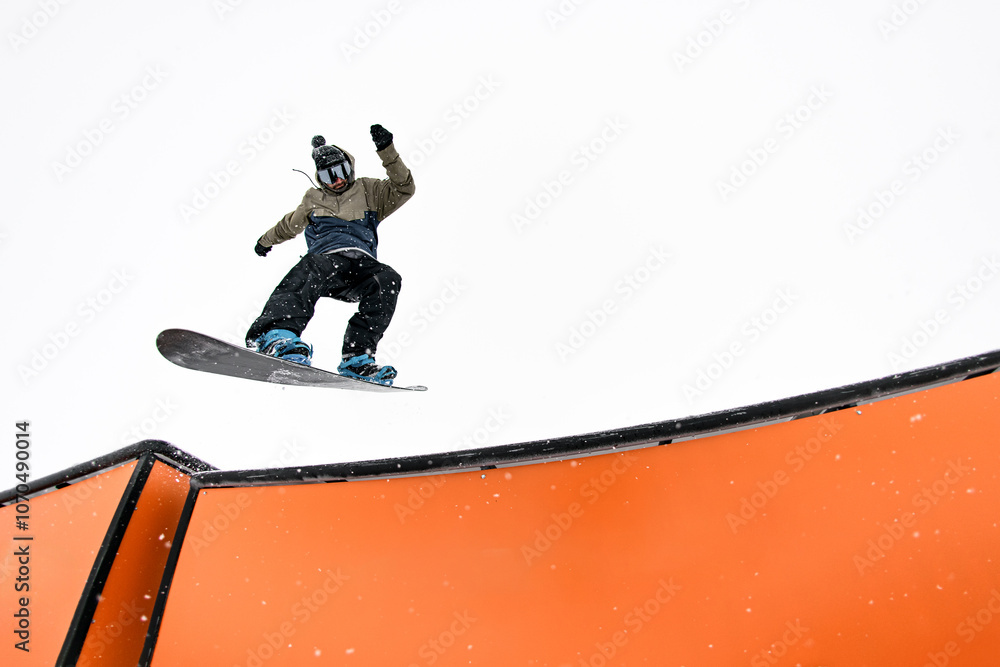 Obraz premium Snowboard pro executes jump into wallride, mastering challenging slope.