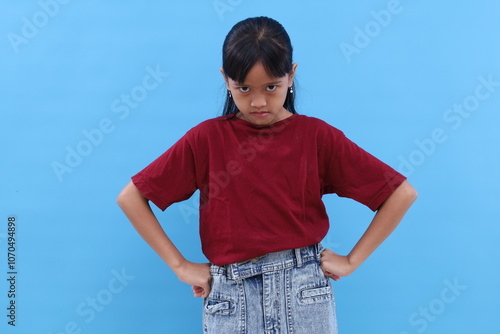 Angry little asian kid showing frustration and disagreement. Isolated on blue background photo