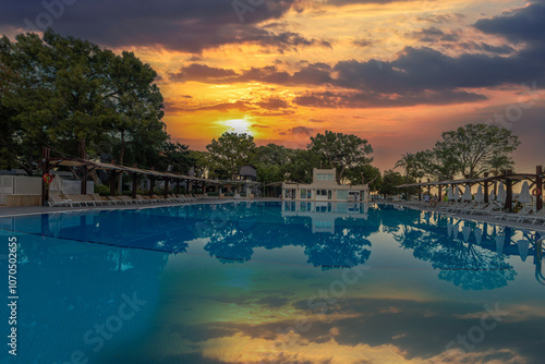 Obraz na płótnie Magnificent view, swimming pool at sunset. Holiday hotel in Antalya. Great relaxation and peaceful atmosphere, palm trees, sun loungers reflections. w salonie