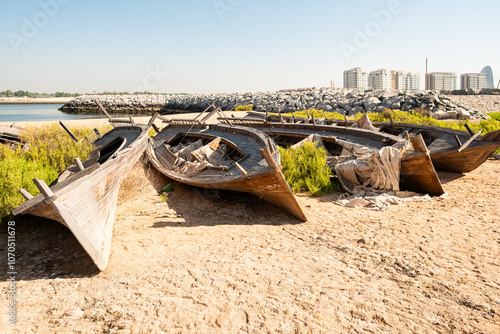 Old abandoned dhow boats standing in row on the shore of bay in UAE. Arabic traditional wooden boat. Old wooden boats left on land near the shore. Boats are badly worn and covered with rust photo