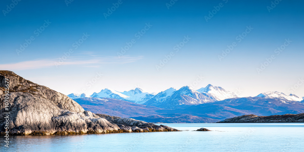 Obraz premium Beautiful snowy mountain landscape reflected in calm water beneath a clear blue sky